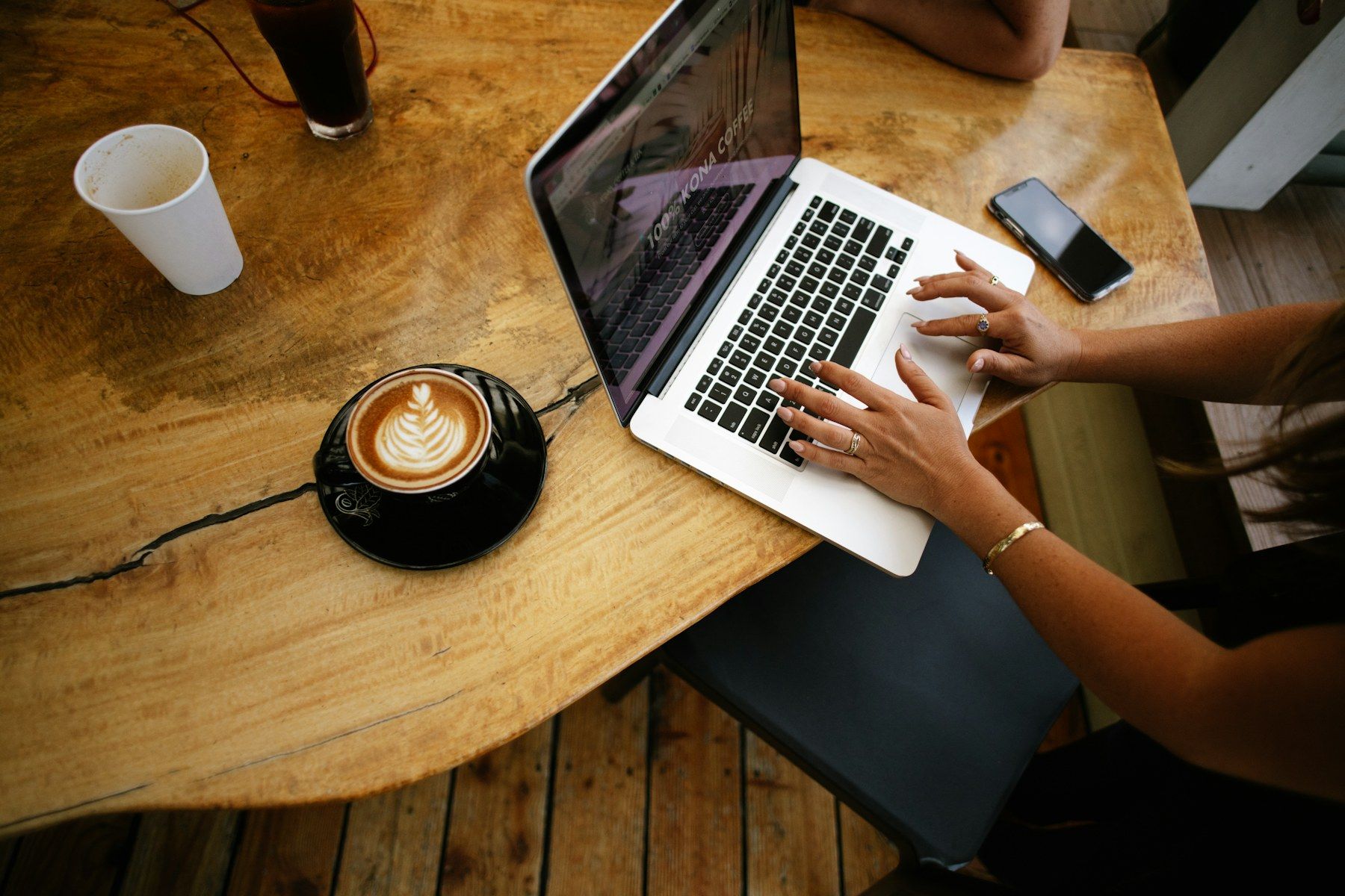 Laptop and a latte on a wooden café table